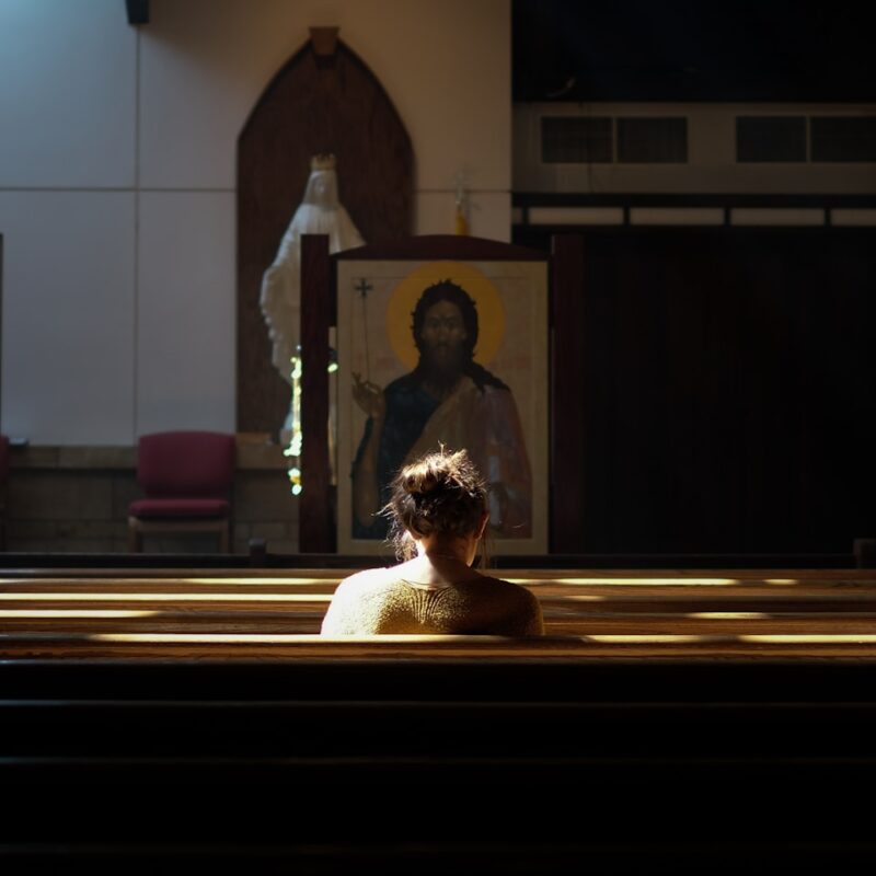woman sitting on church pew during daytime
